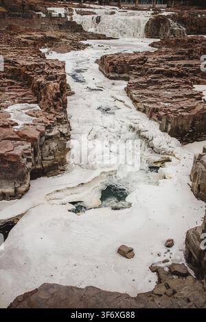 Partially frozen river flowing through a rocky canyon Stock Photo
