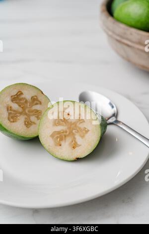 Fresh feijoa fruit cut in half on a white plate Stock Photo