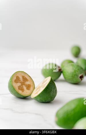 Fresh feijoa fruit cut in half on a white marble surface Stock Photo