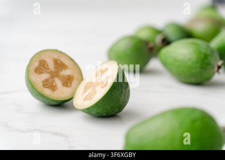 Fresh feijoa fruit cut in half on white marble Stock Photo
