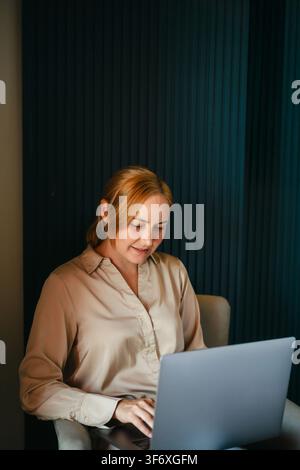Woman smiling while working on a laptop computer Stock Photo