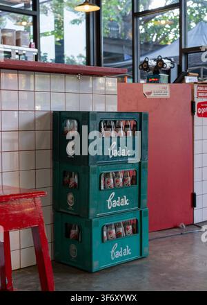 Nostalgic Badak sarsaparilla soda glass bottles in vintage green crates by a tiled counter at a local independent cafe in Surabaya, Indonesia. Stock Photo