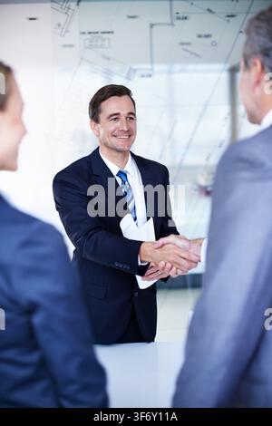 Shaking hands, agreement and business people in office with deal, meeting and blueprint overlay. Welcome, discussion and architect firm with client Stock Photo