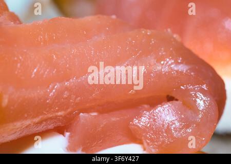 A close-up shot highlights the rich and glossy texture of smoked salmon slices, revealing delicate flesh grains and translucent layers ideal for gourm Stock Photo