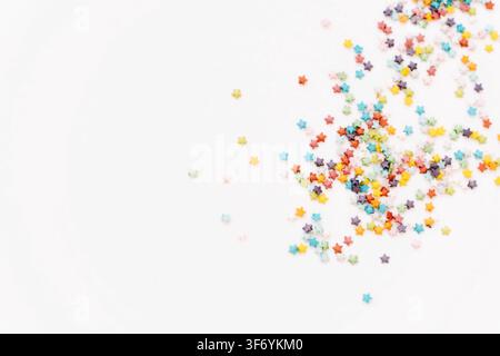 Colorful sugar confectionery stars scattered on a white background in food composition. Colored sugar sprinkles background, Sugar sprinkle dots, decor Stock Photo