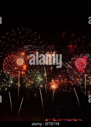 Colorful fireworks exploding in the dark night sky during a festive celebration Stock Photo