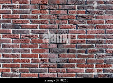 Dark red brick wall with black stains. External wall covering. Full frame, background and texture Stock Photo
