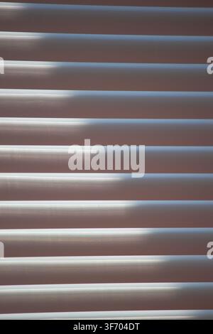 Abstract background of window blinds with sunlight filtering through the slats Stock Photo