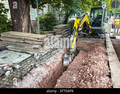 Construction Site on Urban Footpath with Mini Excavator Laying Fiber Optic Internet Cables – Broadband Infrastructure Concept Stock Photo