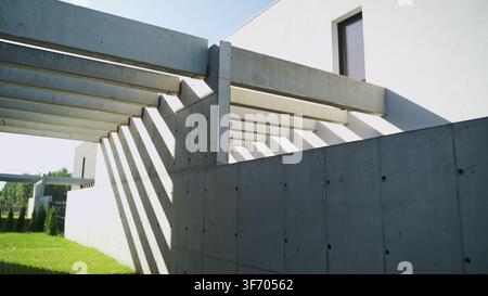 Architectural facade featuring geometric concrete beams casting diagonal shadows on bright white wall in sunlight Stock Photo