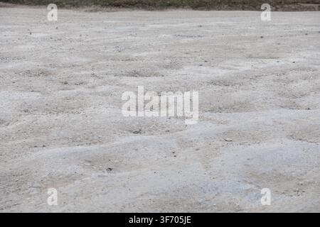 Rippled dirt and gravel ground texture featuring repeating patterns of wear, ideal for illustrating rugged infrastructure, challenging driving conditi Stock Photo