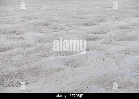 Uneven light grey soil terrain featuring multiple shallow crater depressions and granular texture for a gritty outdoor background that emphasizes eart Stock Photo