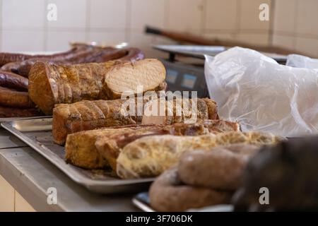 Artisan smoked pork loin and assorted cured sausages arranged on a stainless steel platter in a butcher kitchen, representing high quality culinary in Stock Photo