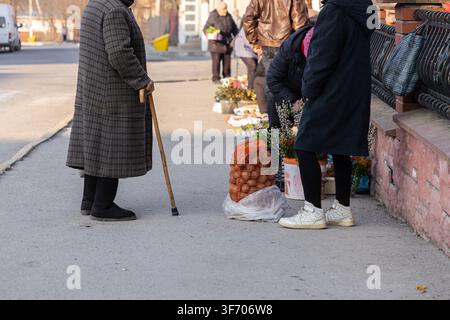 Shoppers buying fresh vegetables from an informal sidewalk market display in an urban area, reflecting typical daily routines, local food access, and Stock Photo