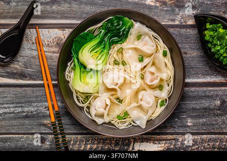 Noodle soup with dumplings (wontons) and cabbage bok choy served in a bowl. Stock Photo
