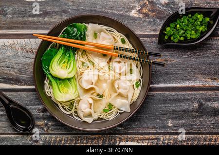 Noodle soup with dumplings (wontons) and cabbage bok choy served in a bowl. Stock Photo