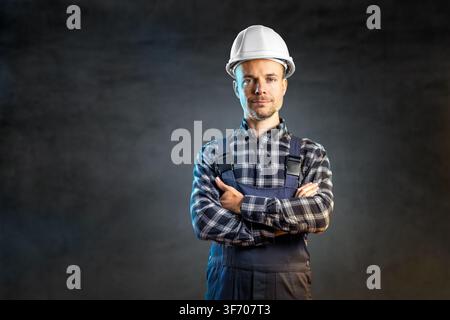 Confident Construction Engineer in White Hardhat and Overalls Looking at Camera Stock Photo