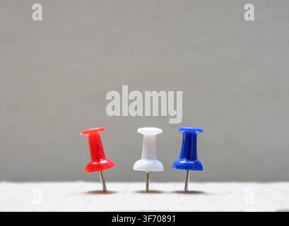 Red, white and blue push pins pinned on white surface Stock Photo