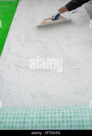 Worker Spreading White Tile Adhesive With Notched Trowel Stock Photo