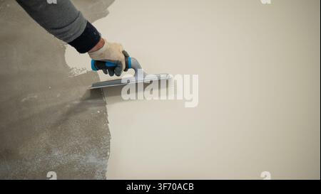 Worker Applying White Liquid Floor Coating With Roller and Trowel Stock Photo