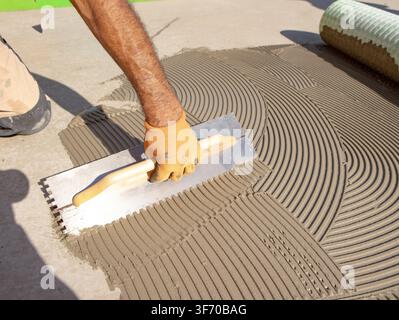 Worker Spreading Tile Mortar Beside Newly Laid Ceramic Tiles Stock Photo