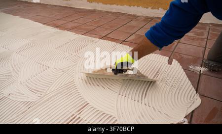 Worker Spreading Tile Mortar Beside Newly Laid Ceramic Tiles Stock Photo