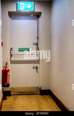 London UK, August 07 2026, Emergency Exit Door With Push Bar And Wall-Mounted Red fire Extinguisher Stock Photo