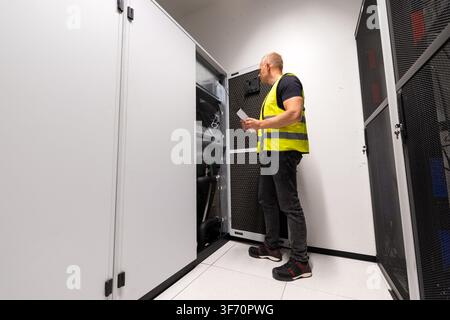 HVAC technician inspecting cooling infrastructure in a data center server room Stock Photo