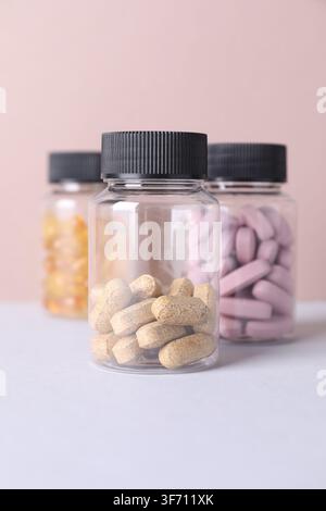 Different pills in medical bottles on light grey table against beige background Stock Photo