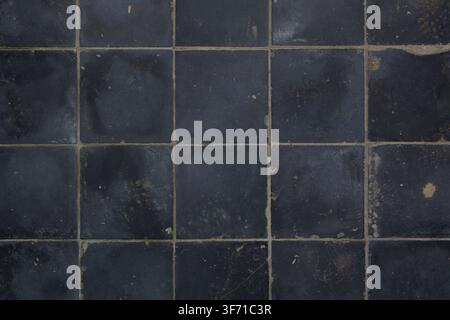 A seamless texture of dark charcoal blue and black distressed square ceramic tiles. Stock Photo