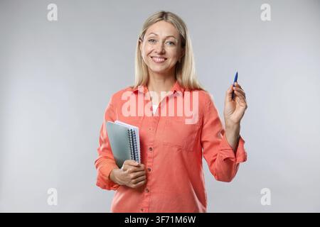 Teacher with notebooks and pen on light grey background Stock Photo