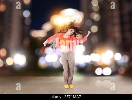 Young woman dancing hip-hop on city street at night Stock Photo