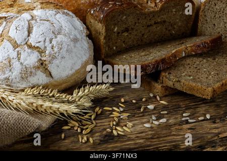 Group of dark breads with wheat, sunflower and rye grains on a wooden vintage table. Stock Photo