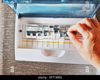 Kirov, Russia - August 24, 2025: A hand is seen adjusting circuit breakers in an electrical panel for managing home electricity and ensuring safety. Stock Photo