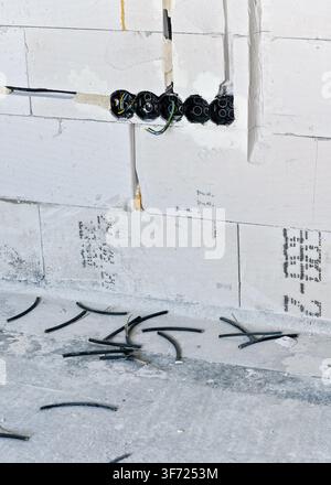 Boxes with cables for electric sockets installed in new house building empty wall Stock Photo