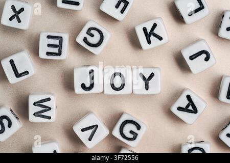 Small white and black bead cubes on a board, letters in middle spell JOY Stock Photo