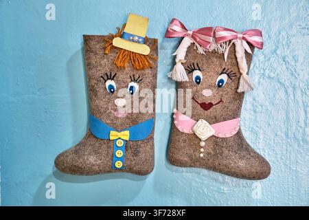 Myshkin, Russia - May 12, 2026: Pair of souvenir Russian felt boots valenki decorated as cute boy and girl characters on blue wall background. Folk cr Stock Photo