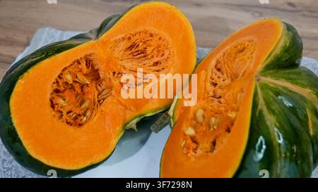 Green Pumpkin Cut in Half Showing Orange Flesh and Seeds Stock Photo