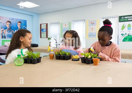 African American female students 2 youth 1 child in sweaters working on seedling trays at school. Classroom, gardening, plants, collaboration, learnin Stock Photo