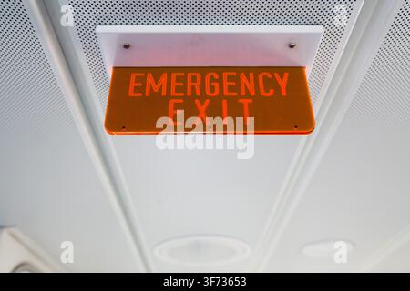An illuminated emergency exit sign aboard an Uber Boat by Thames Clippers river bus, ensuring passenger safety on the River Thames in London. Stock Photo