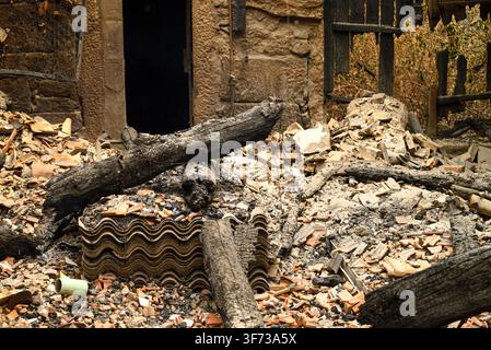 Insurance concept shot showing destroyed home rubble with burnt wooden logs and tiles Stock Photo