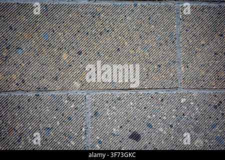 The scene shows a close-up view of a stone pavement on a city street. The stones are arranged in a pattern, creating various textures and shades. Sunl Stock Photo