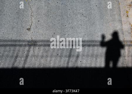 Shadow of a Person and Railing Cast on Asphalt Street in Ciego de Avila, Cuba - July 2026 Stock Photo