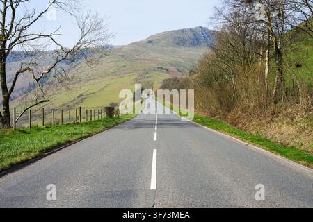 Rural two lane road passing through rugged farmland in Central Wales in springtime Stock Photo