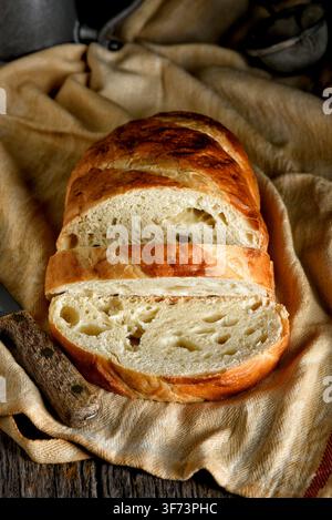 Bread still life. A fresh loaf of Bread in a rustic kitchen setting with two slices cut. Stock Photo