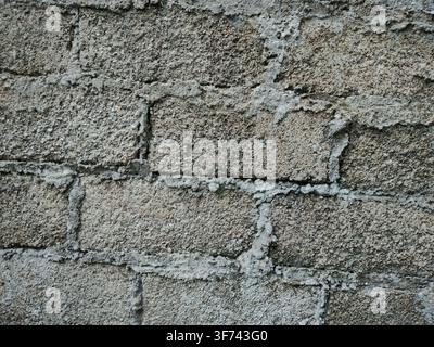 A textured wall built with gray concrete blocks shows visible mortar lines between the rectangular bricks. Stock Photo