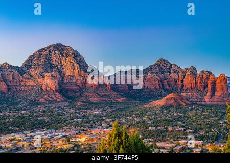 Twilight settles over Sedona as city lights glow beneath Coffee Pot Rock and surrounding red rock formations. Stock Photo