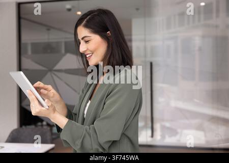 Confident professional businesswoman checking emails on smartphone in modern office Stock Photo
