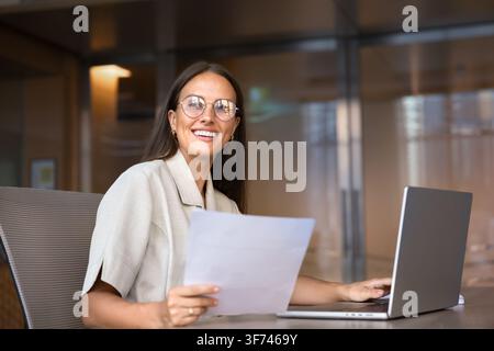 Smiling businesswoman checking documents at office desk Stock Photo