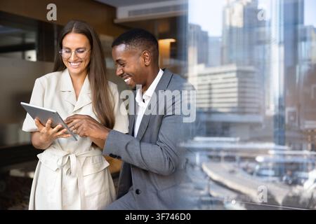 Smiling multiethnic colleagues collaborate on corporate project using digital tablet Stock Photo